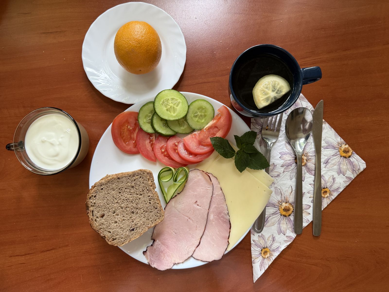 Jogurt naturalny, pomarańcza, chleb żytni, warzywa, wędlina i ser oraz herbata.